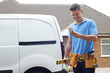 © highwaystarz - Builder With Van Checking Text Messages On Mobile Phone Outside House