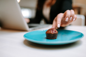 Close-up image of female hand taking delicious muffin with berries.