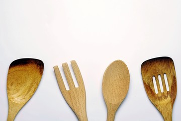 top view image of wooden spoon and wooden fork on the white desk, Different wooden kitchen tools on the table with copy space