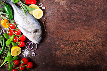 Wall Mural - Fresh uncooked fish, dorado, sea bream with lemon, herbs, vegetables and spices on rustic background. Top view. Free space for your text