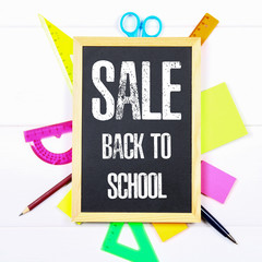 Wall Mural - Chalkboard surrounded by stationery on a white wooden table. Back to school sale.