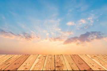 Wall Mural - wooden table on beautiful dramatic sunset sky with orange and blue colored clouds for spring or summ