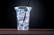 Plastic transparent cup of ice drink with straw isolated on black background. Drink - to go, take away, take out.