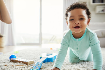 Happy mixed race toddler boy crawling in sitting room