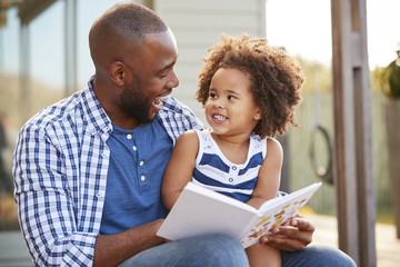 Wall Mural - Young black father and daughter reading book outside