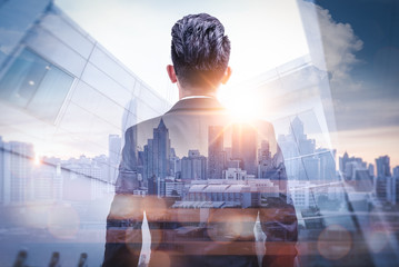 the double exposure image of the businessman standing back during sunrise overlay with cityscape ima
