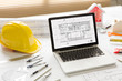 © Somkiat - House plan on laptop monitor with  roll blueprints , small house model and architect equipments on desk at workplace.