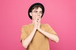 © pantovich - Surprised the guy in glasses standing over pink background covering his mouth with his hands