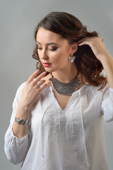 Wall Mural - Portrait of young beautiful woman with brown hair fresh skin wearing accessories and jewelry isolated on a white background