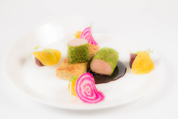 Roast pork tenderloin with crispy potato bread, marinated beetroots and green pepper sauce on a plate on a white background