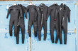 A number of wetsuits drying in summer sun on an old distressed door after use in surfing.