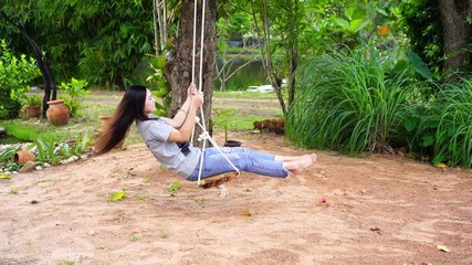 Wall Mural - slow motion of woman playing on swing in garden