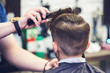 Hairdresser making a hairstyle to a boy in barbershop.
