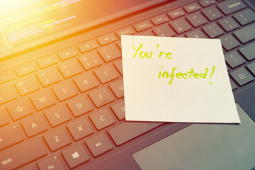 You're infected message concept written post it on laptop keyboard