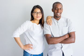 Positive beautiful interracial couple looking at camera. Smiling confident young multiethnic couple standing in studio. Relationship concept