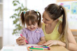 © Oksana Kuzmina - Happy family mother and kid daughter together paint. Woman helps child girl.