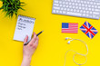 Learn new english vocabulary. Learn landuage concept. Computer keyboard, british and american flags, notebook for writing new vocabulary on yellow background top view