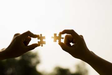 Closeup hands of woman and man connecting jigsaw puzzle