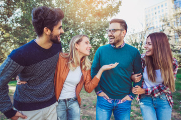 Wall Mural - Group of young people walking through park. Friends having fun outdoor