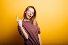 Cheerful Beautiful Young Woman Showing Rock And Roll Gesture Over Yellow Background