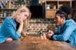 side view of multiethnic young couple playing chess together in kitchen