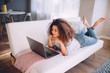 © Criene Images - african happy woman lying on couch with laptop