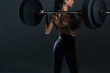 © LIGHTFIELD STUDIOS - back view of female bodybuilder posing with barbell, isolated on grey