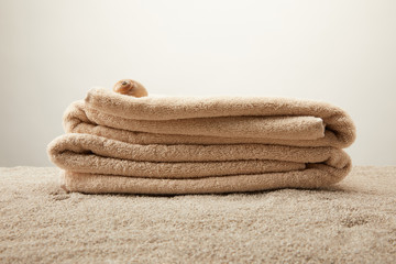 Wall Mural - close up view of pile of towels with seashell on sand on grey backdrop