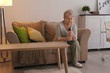 © Africa Studio - Religious elderly woman praying with Bible on sofa at home