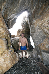 A young man posing in a natural hole in the rock at seaside