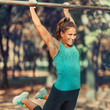 © Microgen - Woman Exercising on Horizontal Bar Outdoors in The Fall