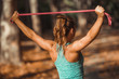 © Microgen - Woman Exercising With Elastic Band Outdoors in The Fall