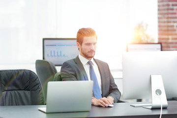 Canvas Print - Young businessman using a computer on his desktop.