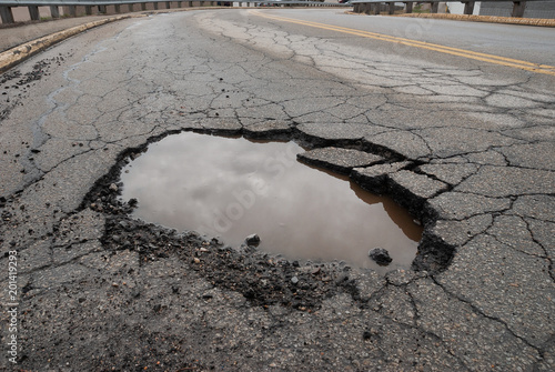 Fotografía Pothole in road with broken asphalt after spring thaw