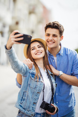 Sticker - Happy tourists taking selfie on city street. Couple have great summer vocation in new destination