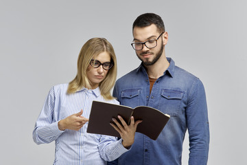 a young couple in glasses and business wear a man and a woman in work together with the project and with a smile studying data. 