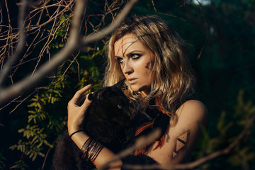 Beautiful young woman model portrait with black cat in forest. witchcraft concept