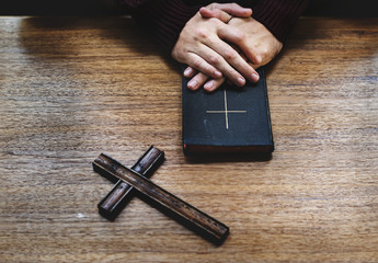 Canvas Print - Hands over bible on wooden table