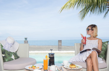 Woman relaxing at the poolside and sea view with morning coffee breakfast sunny day outdoor girl at travel exotic resort