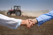 Farmers Shking Hands In Front Of Tractor