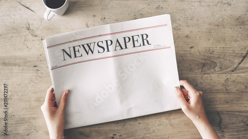 Cuadros en Lienzo Woman reading newspaper on wooden background
