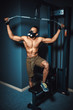 © Oleksandr - african american athletic man poses near to pull down machine black fitness man in mask and pull down machine