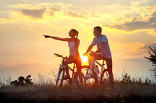 Silhouette Of Happy Couple On Bicycles At Sunset