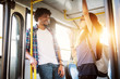 © dusanpetkovic1 - Young beautiful charming and joyful couple is standing in a bus near the doors talking and having a laugh as they travel.