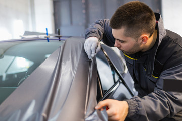 Wall Mural - Car wrapping specialist putting vinyl foil or film on car. Selective focus. 