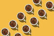 Cup concept. White cups with coffee beans on yellow background.  Creative style.