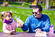 © Guliia - Daughter and dad are having picnic in the park on a sunny spring day
