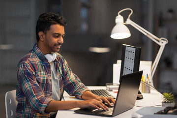 Wall Mural - deadline, technology and people concept - creative man with laptop computer working at night office