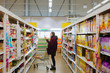 © bella.elisichenko - Woman in supenmarket with shopping trolley choosing products. Girl in market.