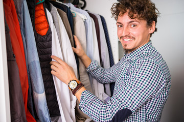 Young man looking for shirts in the dressing room